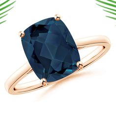 a ring with a blue stone on it and palm leaves in the background, all around