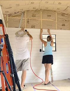 two people working on the inside of a house under construction, one man is painting the ceiling