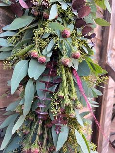 a bunch of green and purple flowers hanging from a wooden pole in front of a building