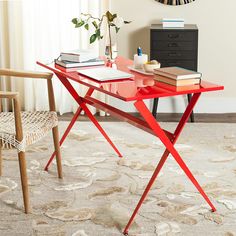 a red table sitting on top of a rug next to a wooden chair and desk