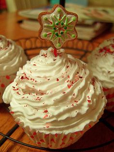 three cupcakes with white frosting and sprinkles on a wire rack