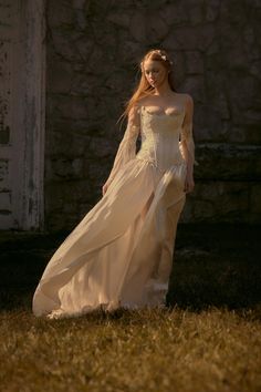 a woman in a white dress is walking through the grass with her long flowing hair