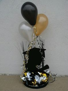 a black and gold balloon is in the center of a vase with some foiled confetti