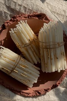 some white sticks are in a bowl on a cloth tablecloth and there is no image here to provide a caption for