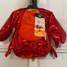 an orange and red jacket hanging from a hook on a white wall with a tag attached to it