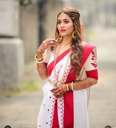 a woman in a red and white sari is posing for the camera with her hands on her hips