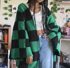 a woman with dreadlocks wearing a green and black checkered cardigan sweater