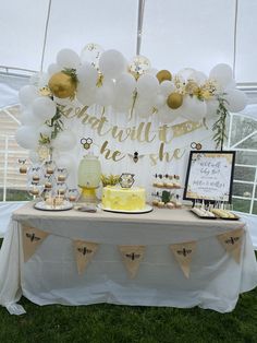 a table topped with cake and desserts under a tented area filled with balloons