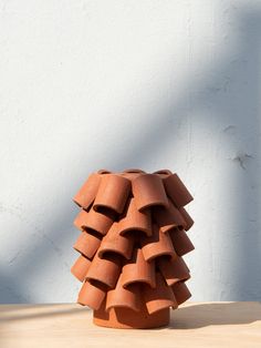 a clay sculpture sitting on top of a wooden table next to a white stucco wall