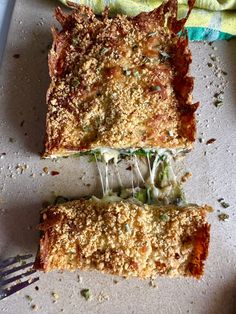 two slices of pizza sitting on top of a cutting board next to a knife and fork