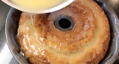 a person pouring syrup over a bundt cake in a pan on top of a stove