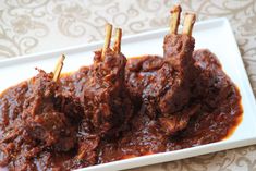 three pieces of meat on skewers in a red sauce with toothpicks sticking out of it