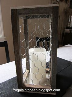 a candle holder made out of chicken wire is sitting on a table in front of a window