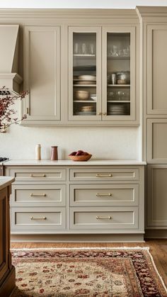 a kitchen with white cabinets and wooden floors, an area rug in front of the counter