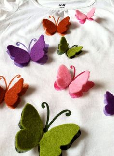 several different colored felt butterflies on a white t - shirt