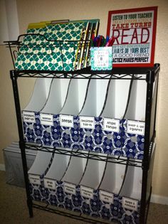 a book rack with many books and binders on it in front of a wall