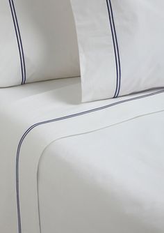 a bed with white sheets and blue trim