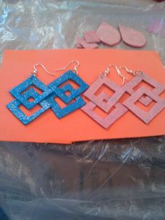 two pairs of blue and pink earrings sitting on top of an orange piece of paper