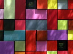 a multicolored wall with windows and trees in the backgroung area