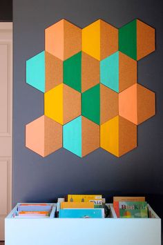 a colorful wall hanging on the side of a gray wall next to a white table