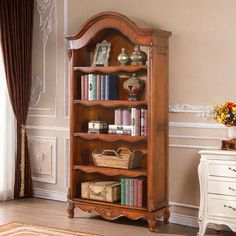 a wooden bookcase with many books on it in a room next to a window