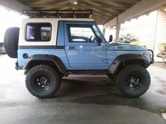 a blue and white jeep is parked in a garage with the door open to let people know where they are going