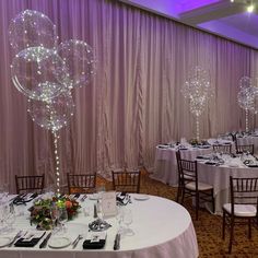 a banquet room set up with round tables and balloons