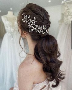 a woman wearing a bridal hair comb in front of wedding gowns and dresses