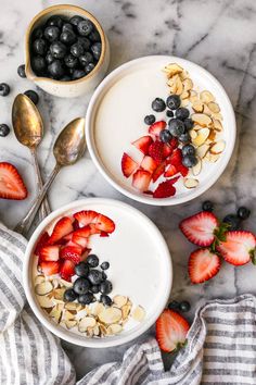 two bowls filled with yogurt and berries on top of a marble countertop