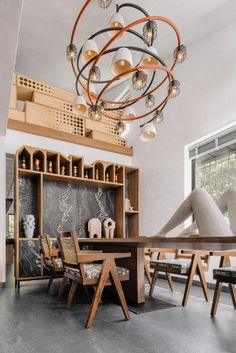 a wooden table sitting under a light fixture in a room with lots of shelves and chairs