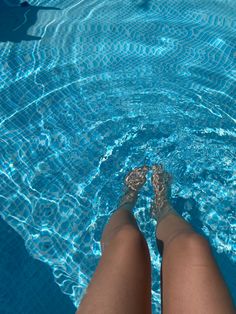 a woman's legs in the water near a swimming pool with clear blue water