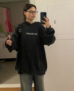 a woman taking a selfie in front of a mirror wearing a black hoodie