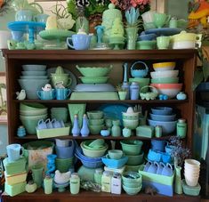 a shelf filled with lots of green and blue dishes