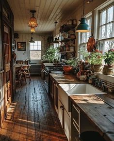 an old fashioned kitchen with wooden floors and lots of potted plants on the windowsill