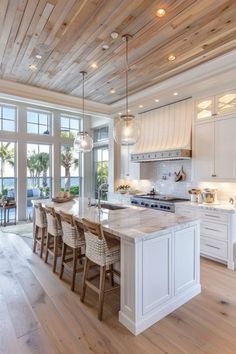 a large kitchen with white cabinets and wooden floors, along with an island in the middle