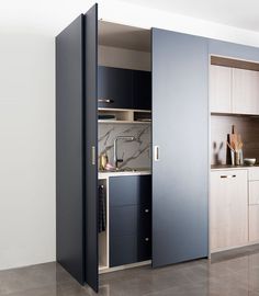 an open door to a kitchen with marble flooring and blue cabinets in the background