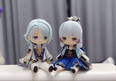 two anime figurines sitting on top of a white table next to each other