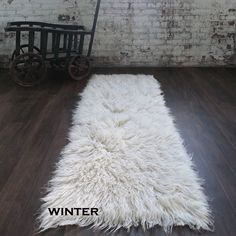 a white rug is on the floor in front of a brick wall and wooden floors