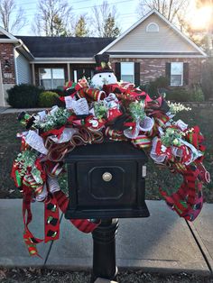 a mailbox decorated with christmas wreaths and ribbons in front of a house on a suburban street