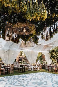 an outdoor dining area with white drapes and hanging oranges on the ceiling, surrounded by greenery