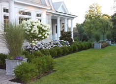 a white house with lots of flowers in the front yard