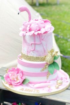 a pink and white cake sitting on top of a wooden table next to a tent