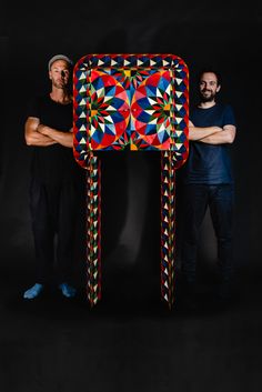 two men standing next to a colorful object