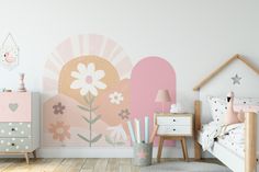 a child's bedroom decorated in pastel pink and grey with flowers on the wall