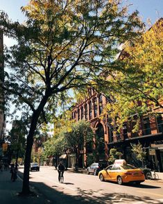 a yellow taxi driving down a street next to tall buildings