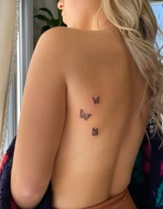 the back of a woman's body with three butterflies on her left shoulder and chest