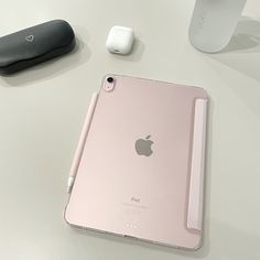 an apple ipad is sitting on a table next to ear buds and a remote control