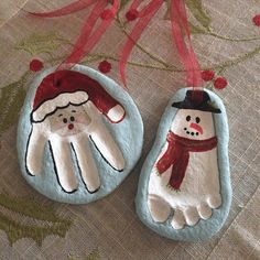 two handmade christmas ornaments hanging from a red ribbon on top of a table cloth