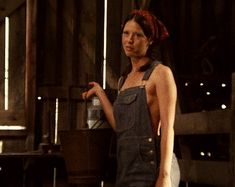 a woman in overalls standing next to a stove