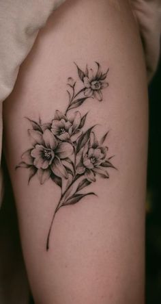 a black and white flower tattoo on the right arm, with flowers growing out of it